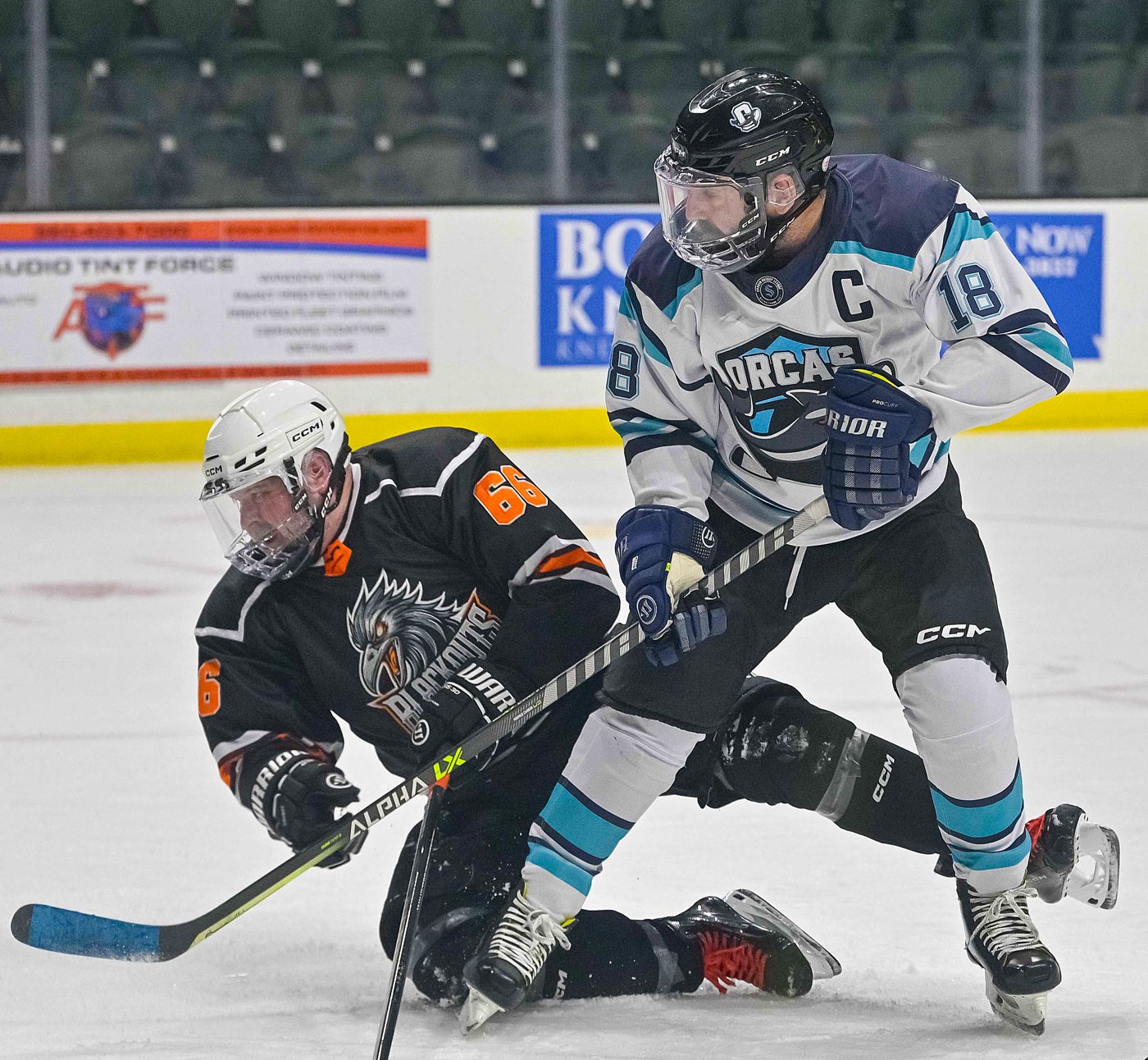Adam Levermore, number 18 for the Orcas, battling for the puck against a Blackouts player
